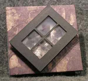 Starburst book w/ image of young Lee reading newspaper behind black window frame. Not visible are strips of text, curled and loose in window space.